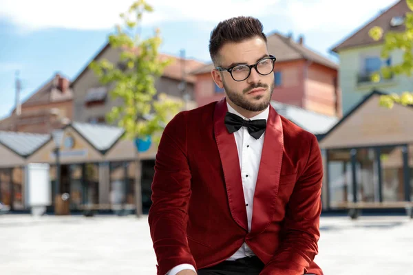 Giovane uomo premuroso che indossa uno smoking di velluto rosso e pensa — Foto Stock