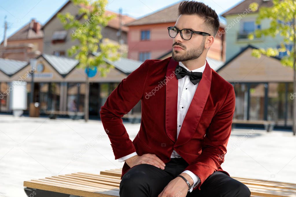 concerned young elegant man sitting on wooden bench