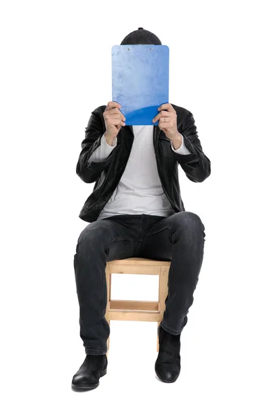 Сидячий випадковий чоловік, що закриває обличчя з буфером — стокове фото