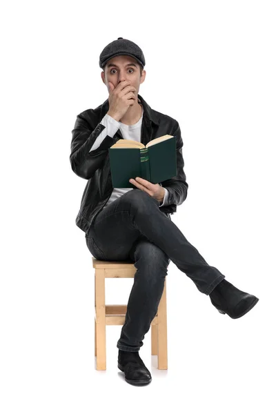 Sitzender lässiger Mann mit seinem Buch schockiert — Stockfoto