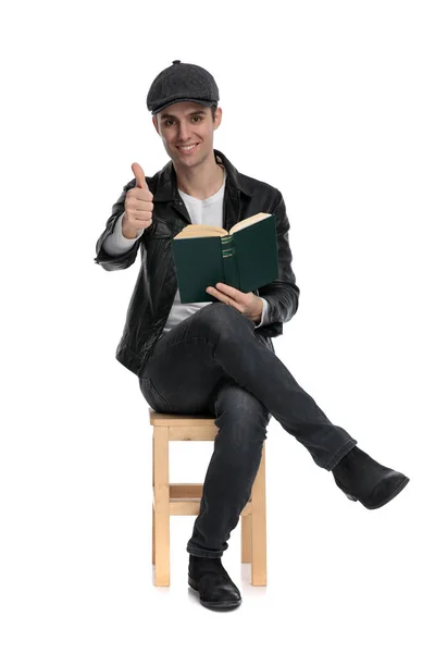 자신감 있는 표지판으로 책을 들고 앉아 있는 캐주얼 한 남자 — 스톡 사진
