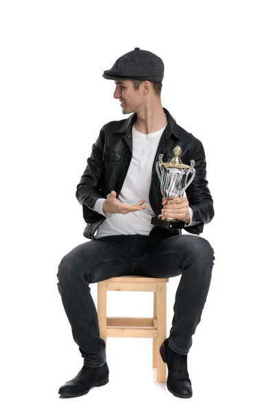 Seated casual man presenting his cup and looking sideways — Stock fotografie