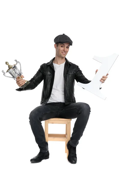 Seated casual man presenting his number one and cup cocky — Stockfoto