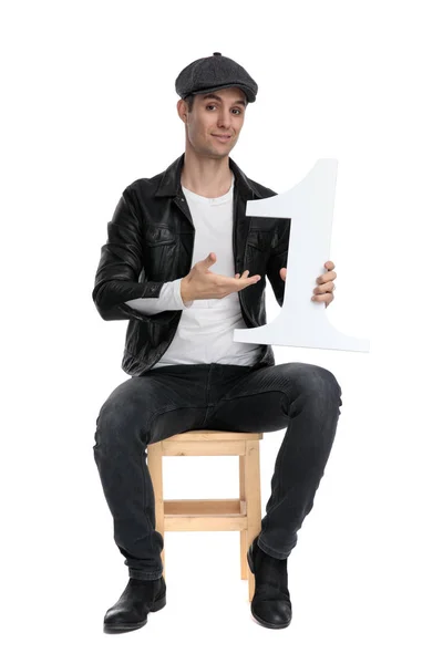 Sentado casual homem apresentando seu número um arrogante — Fotografia de Stock