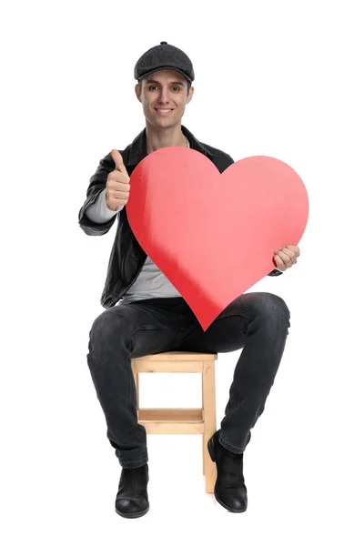 Sitzender, lässiger Mann mit einem großen Herz und Ok-Zeichen — Stockfoto
