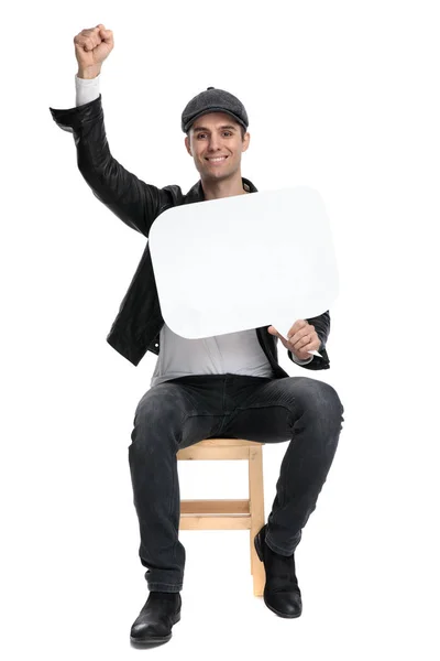 Seated casual man holding speech bubble and one fist up — 스톡 사진