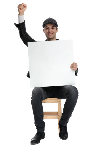 Sittande casual man Holding Billboard och en knytnäve upp victoriously — Stockfoto