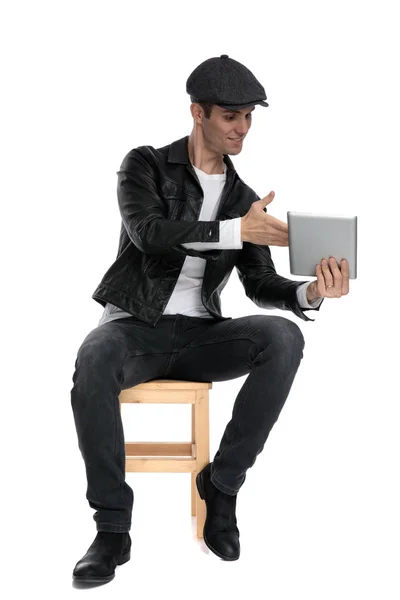 Sentado hombre casual presentando y mirando su tableta feliz — Foto de Stock