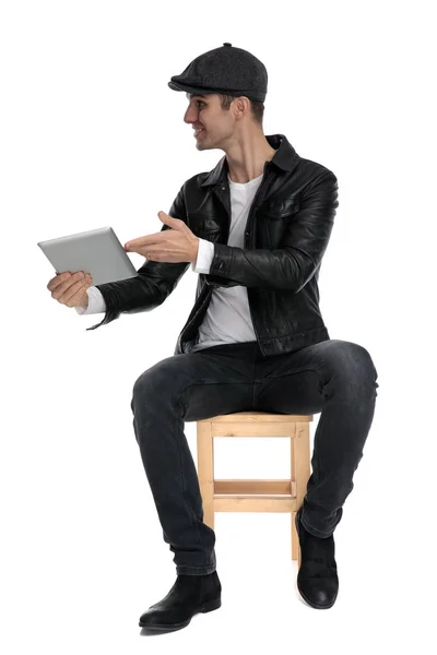 Seated casual man presenting his tablet to a side happy — Φωτογραφία Αρχείου