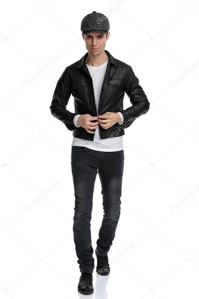 casual man walking while closing his jacket confident