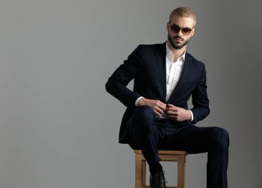 işadamı oturur ve ceketinin düğmesini tutan emin