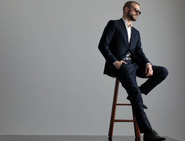 bir eliyle cebinde oturan işadamı ileriye bakarak optimi