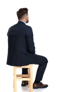 ahşap sandalyede oturan genç işadamının arka görünümü