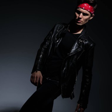 gri arka planda deri ceket giyen dramatik serin adam