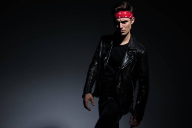 gri arka planda deri ceket giyen kibirli serin adam