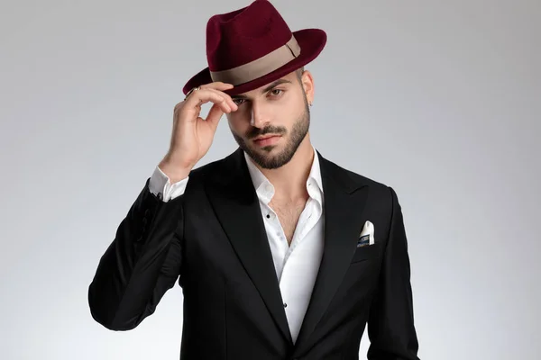 Businessman standing and fixing his hat while looking at camera — Stock Photo, Image