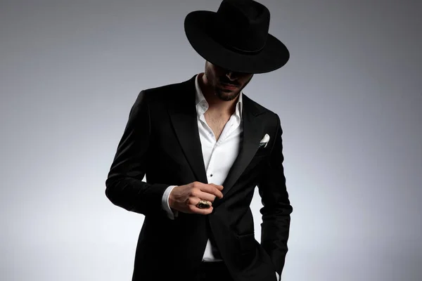 Таинственный молодой элегантный мужчина в смокинге и черной шляпе — стоковое фото