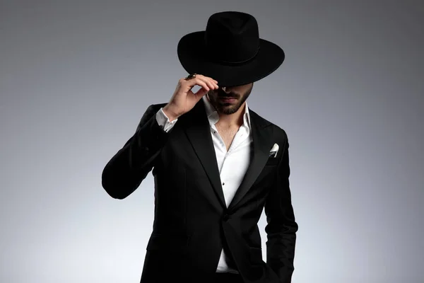 Mysteriöses Mode-Model zieht Hut auf grauem Hintergrund — Stockfoto