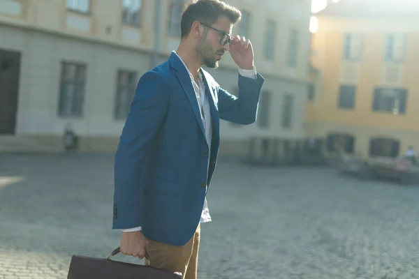 Attraktiver junger Mann befestigt Brille im Freien in einer urbanen Szene — Stockfoto