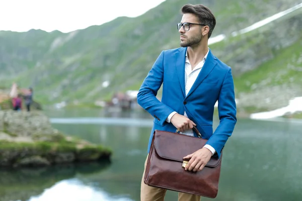 Hombre casual inteligente sosteniendo la maleta y mirando a un lado — Foto de Stock