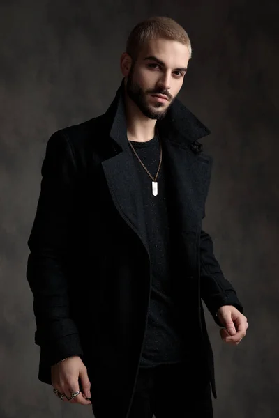 Випадковий молодий чоловік у довгому пальто на сірому фоні — стокове фото