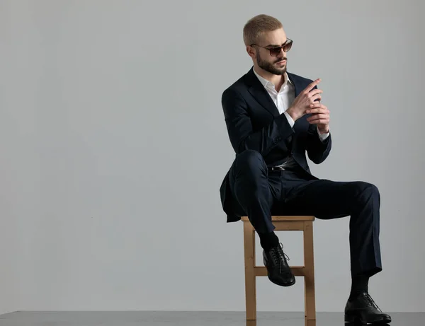Hombre de negocios sentado y cogido de la mano mientras mira hacia los lados pluma — Foto de Stock