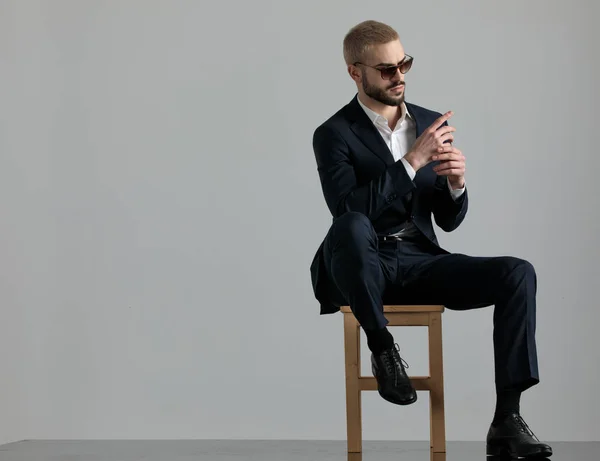 businessman sitting and holding hands while looking sideways pen