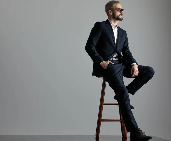 businessman sitting with one leg resting looking ahead confident