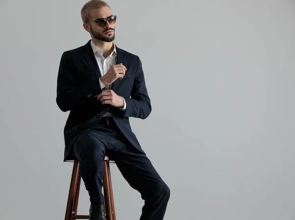 Hombre de negocios sentado y fijando su manga pensativo — Foto de Stock