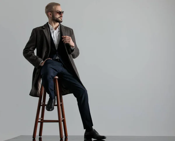 businessman sitting with one leg resting and hand in pocket