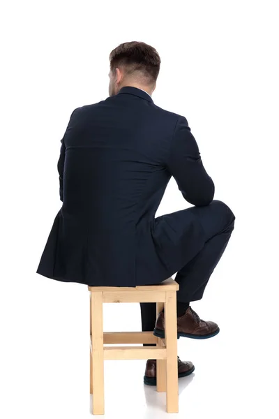 Vista trasera del joven hombre de negocios sentado en una silla de madera — Foto de Stock