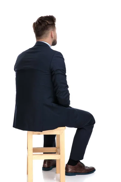 Tillbaka syn på unga affärsman sitter på trästol — Stockfoto