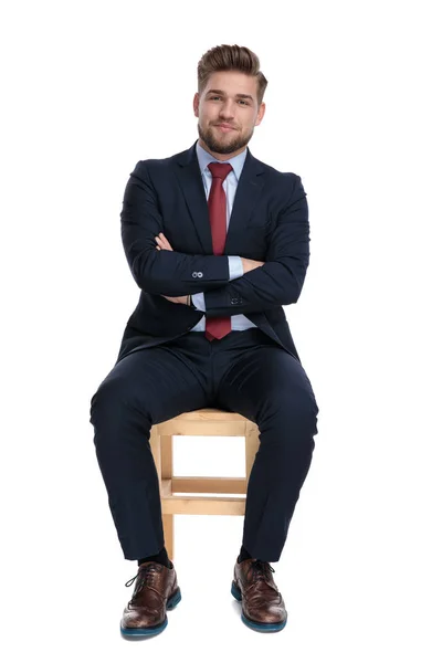 Щасливий молодий бізнесмен сидить на дерев'яному стільці — стокове фото
