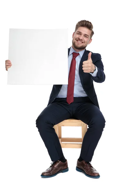 Счастливый молодой бизнесмен держит доску и делает большие пальцы вверх знак — стоковое фото