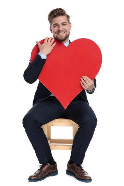 Szczęśliwy młody biznesmen trzyma czerwone serce w Studio — Zdjęcie stockowe