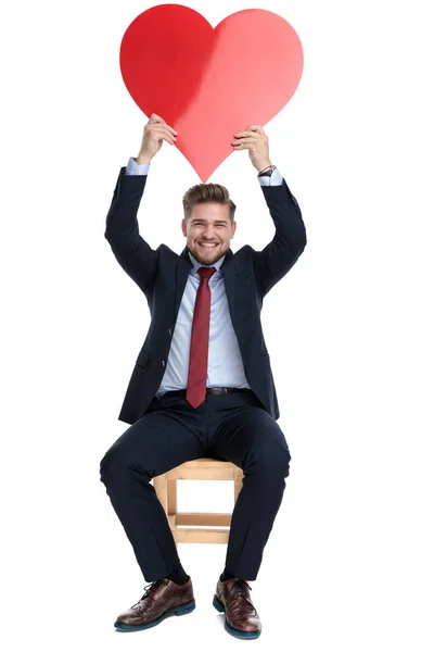 Feliz joven empresario sosteniendo gran corazón rojo en el estudio — Foto de Stock