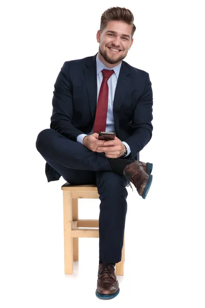 Happy young businessman holding phone in hands — Stock Photo, Image