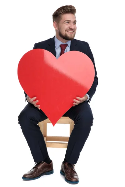 Jovem empresário feliz segurando coração vermelho no estúdio — Fotografia de Stock