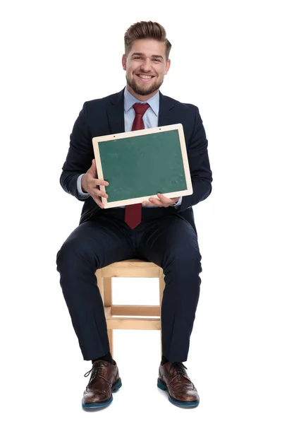 Happy young businessman holding an empty blackboard — Stock Photo, Image