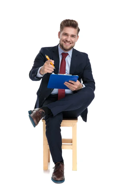 Happy young businessman holding clipboard in studio — Stock Photo, Image