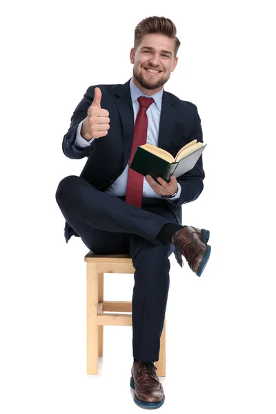 Hombre de negocios sosteniendo libro y haciendo pulgares hacia arriba signo — Foto de Stock