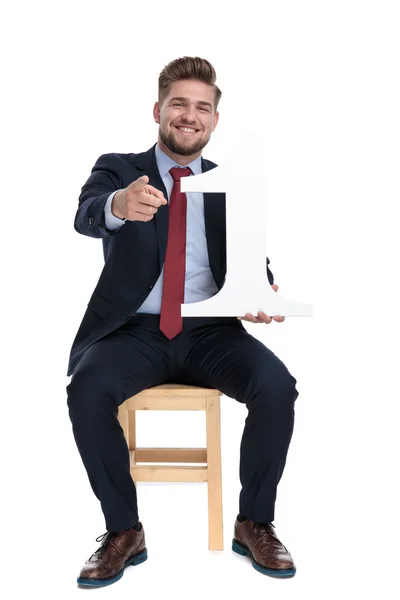 Счастливый молодой бизнесмен держит знак номер один — стоковое фото