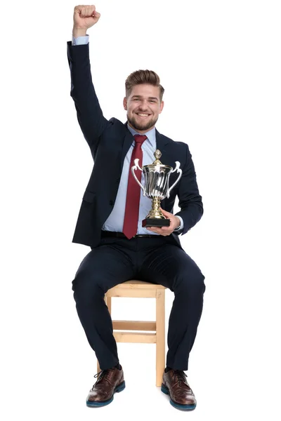 Hrdý podnikatel držící trofej a držící ruku ve vzduchu — Stock fotografie