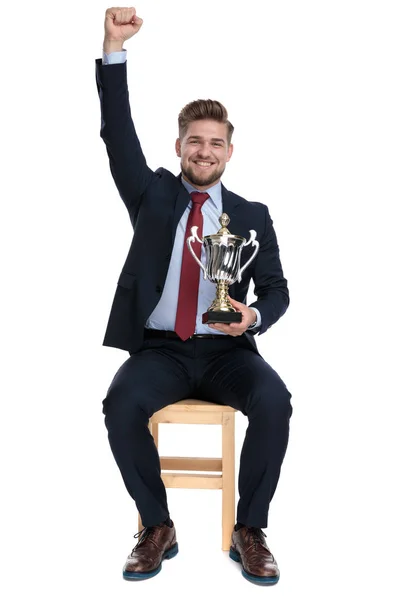 Proud businessman holding trophy and holding hand in the air — Stock Photo, Image