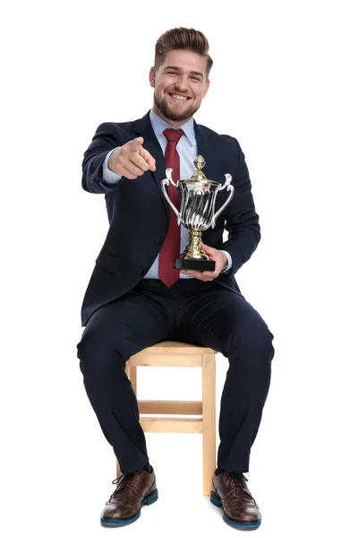 Joven empresario emocionado sosteniendo trofeo y señalando el dedo —  Fotos de Stock