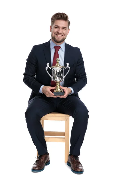 Proud young businessman holding trophy in studio — Stock Photo, Image