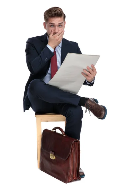 Шокований молодий бізнесмен сидить на дерев'яному стільці — стокове фото