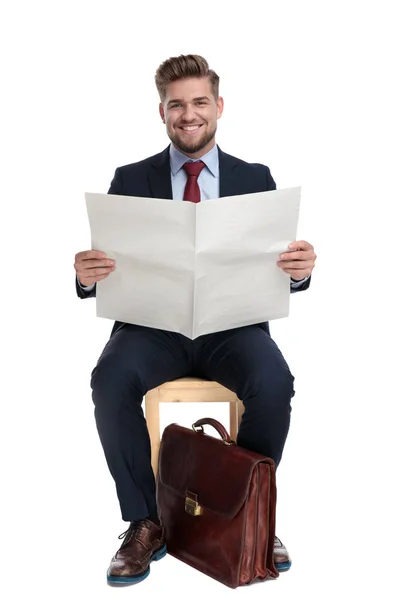 Glücklicher junger Geschäftsmann hält Zeitung im Studio — Stockfoto