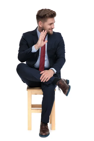 Jovem empresário feliz sentado na cadeira e acenando — Fotografia de Stock
