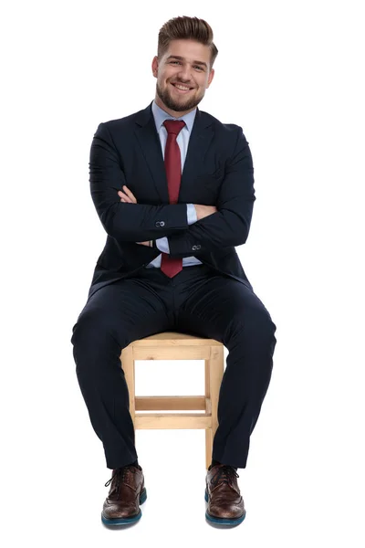 Щасливий молодий бізнесмен сидить зі складеними руками — стокове фото